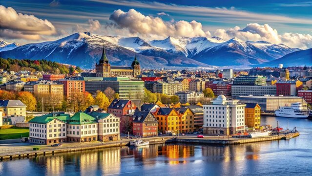 Vibrant colorful buildings line the scenic waterfront of Oslo, Norway's capital, with majestic snow-capped mountains rising in the background under a bright blue sky.