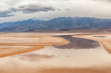 Landscape of Cottonball Basin and the Panamint Mountains with reflections in calm water, Death Valley National Park, California, USA