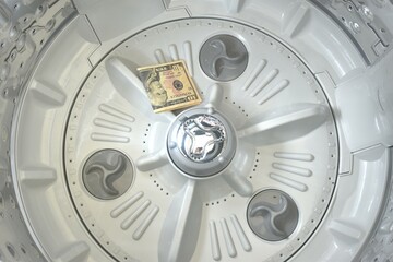 ten US dollar banknote dropping on bottom washing machine drum after cleaning