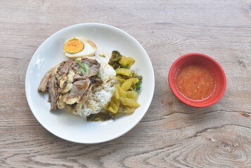 braised  slice beef stew black Chinese herb soup topping brown boiled egg half cutting eat couple pickled cabbage dipping spicy sour chili sauce on plain rice in plate 