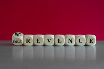 Symbol for a better revenue. Turned a wooden cube and changes words small revenue to big revenue. Beautiful red background. Business and big revenue concept.