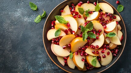 A flat lay of a colorful autumn fruit salad, with slices of apples, pears, and pomegranate seeds, garnished with mint leaves