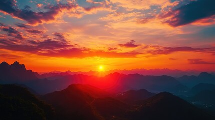 Fototapeta premium Sunset over a mountain range with vibrant sky and glowing sun.