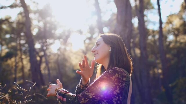 Young beautiful woman dancing in the forest with her hand raised. Concept of balance, harmony and health.