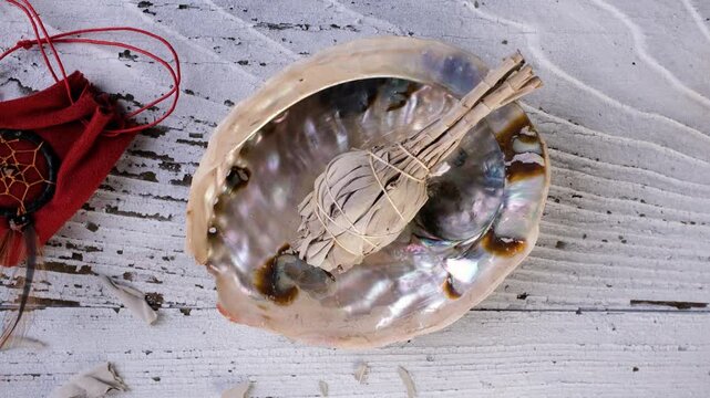 Push in shot of a white sage smudge stick (Salvia apiana) in an abalone shell