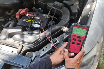 Technician diagnosing old battery health of automobile with instrument. Test result suggested battery is weak with 9 percent health level.