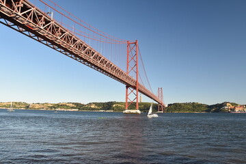 Detailed view looking up at the April 25 Bridge in Lisbon Portugal with a clear blue sky background. 