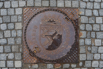 A manhole cover with the coat of arms of Sibiu, also known as Hermannstadt, Transylvania, Romania