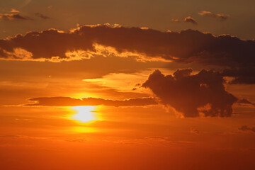 Sunset with dramatic clouds in orange sky. Nature photography. Twilight sky landscape for design and print.