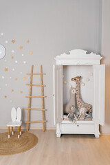 White dresser with a giraffe stuffed animal inside. The room is decorated with stars and a ladder