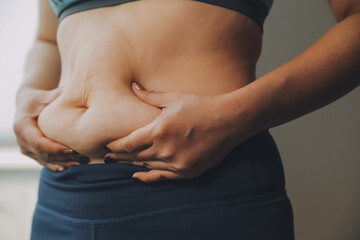 Naklejka premium fat woman, fat belly, chubby, obese woman hand holding excessive belly fat with measure tape, woman diet lifestyle concept