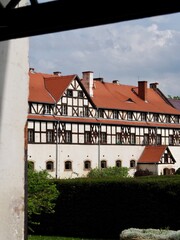 A beautiful historic building with distinctive red roofs and intricate architectural details stands against a backdrop of a cloudy sky, highlighting the charm and elegance of heritage structures.
