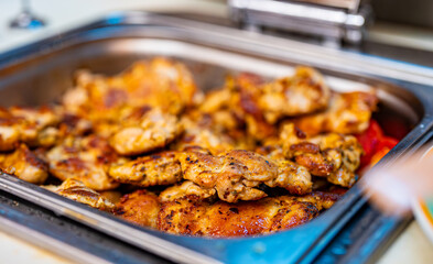 Lots of fried chicken thighs in a metal tray.