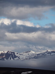 An awe-inspiring image of majestic snow-covered peaks under a dramatic cloudy sky, highlighting the grandeur and impressive scale of the mountain range.