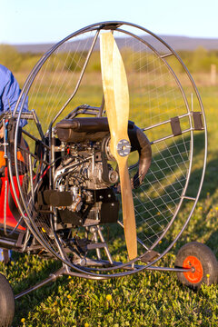 Paragliding machine for paragliding flights on green grass against the bright sun. Preparing paralet with a gasoline engine for flights. Extreme sports