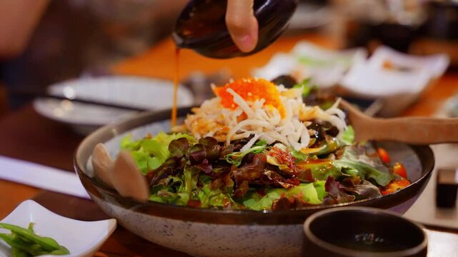 Close-up of pouring sauce over a Japanese salad, featuring fresh vegetables and vibrant ingredients. Highlighting the rich, savory sauce drizzling over crisp, colorful salad. High quality 4k footage