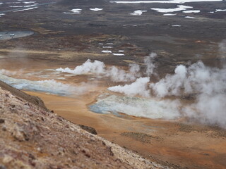 A striking display of geothermal steam venting from the rugged and colorful volcanic landscape, displaying the raw power and beauty of Earth's geothermal activity.