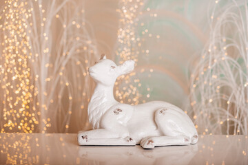 A charming white deer figurine set against a soft background with bokeh lights, perfect for Christmas and winter-themed decorations. 