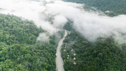 Aerial view of the Pacuare River bed surrounded by trees in the middle of the Caribbean jungle with mountains and fog in the background in the province of Limón in Costa Rica