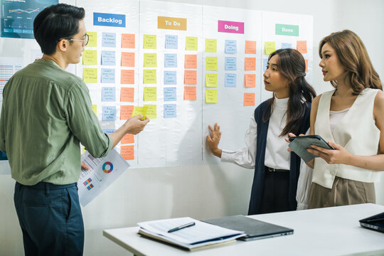 brainstorming session, using sticky notes on a task board (kanban) to organize ideas and workflow in a modern office