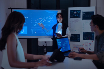 asian leader woman present  business presentation in a dimly lit office, analyzing financial charts...