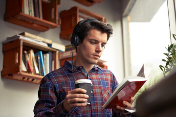 Man, headphones and tea for book at cafe, literature and student to study on campus. Male person,...