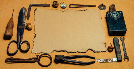 Rustic crafting background with vintage tools and a sheet of old paper on a wooden desk