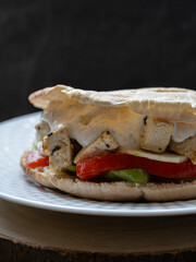 Vertical photo of vegetarian sandwich with grilled vegetables, tofu and yogurt sauce. black background with copy space