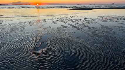 Sunset over the sea. Sea beach at the setting sun.