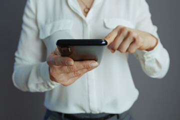 Stylish woman worker using smartphone isolated on grey