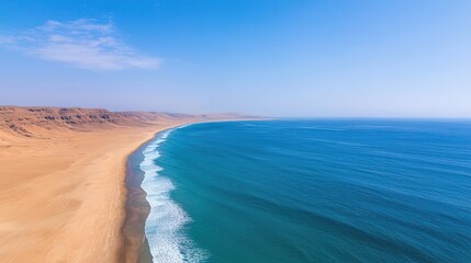 Aerial view of a sandy beach meeting a turquoise ocean under a clear blue sky.