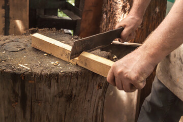 Man's hand cuts wooden slats with a metal cleaver. Close-up