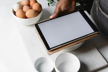 Baker using a tablet device in the kitchen, tech device being used in the kitchen