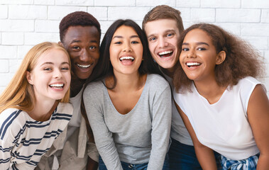 Portrait of happy multiethnic young friends students having fun over white wall background, close up