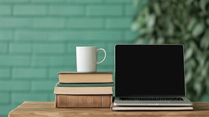 A laptop is on a table with a stack of books and a white coffee cup
