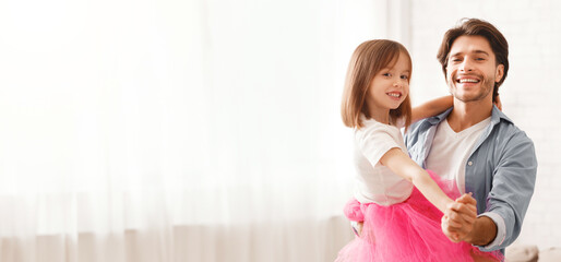 Joyful father and little daughter dancing waltz at home, dad holding girl