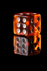 an amber-colored translucent six-sided D6 dice with white dots showing six dots, on a black background with a reflection