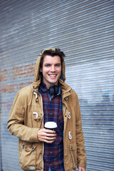 Outdoor, fashion and portrait of man, smile and commuting in morning, happy and confident with headphones. Road, coffee and winter clothes for person, chilling and joy in New York, cool and stylish