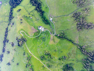 Aerial view of cottage in Swiss alps with road through mountains.