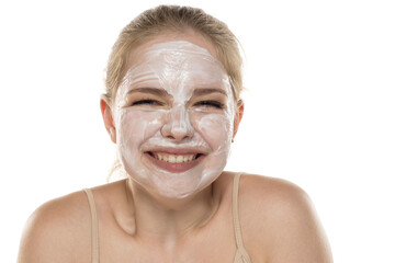 Beautiful happy young woman posing with a facial mask on her face. Skin care and treatment, spa, natural beauty and cosmetology concept