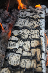 Close up image of a flame in a fireplace. Burnt wood and orange fire.