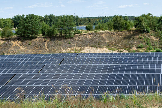 Photovoltaik Freifl&auml;chenanlage; ehemalige Kiesgrube am Waldrand; im Hintergrund Windr&auml;der eines Windparks