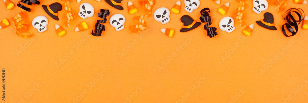 Poster halloween top border of black, white and orange color candy and ribbon. above view on an orange bann