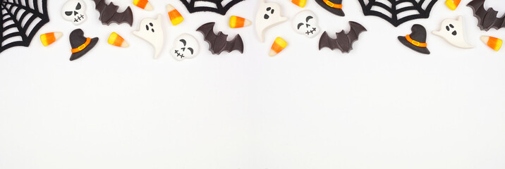 Halloween top border of black, white and orange color candy and spider webs. Overhead view on a...