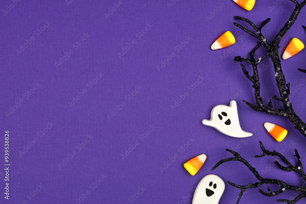 Poster halloween side border of spooky black branches and candy. overhead view on a purple background with 