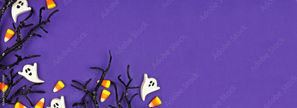 Poster halloween corner border of spooky black branches and candy. top view over a purple banner background