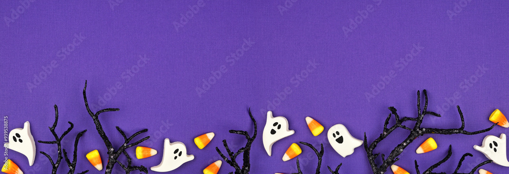 Poster halloween bottom border of spooky black branches and candy. top down view over a purple banner backg