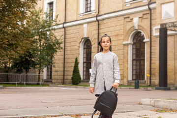 Fototapeta premium A young teenage girl goes to school with a backpack. A teenage student or a schoolgirl. The concept of education.