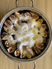 Top view of a pan filled with raw figs, sugar and lemon: recipe for caramelised figs