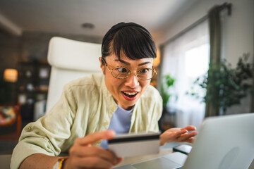 mature happy japanese woman buy online on laptop with credit card